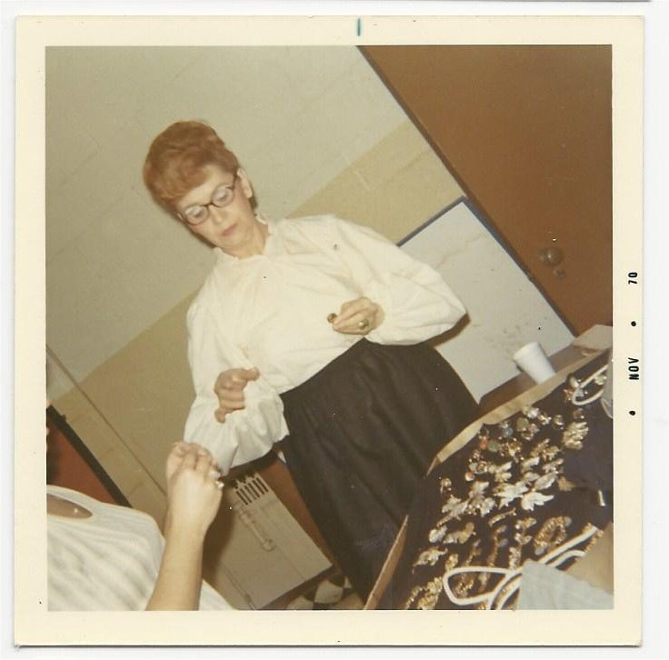 Virginia Hutchens, as a Schtettle member, preparing her inventory of costume jewelery for sale during preperformance welcoming of the audience in the lobby and during the intermission
